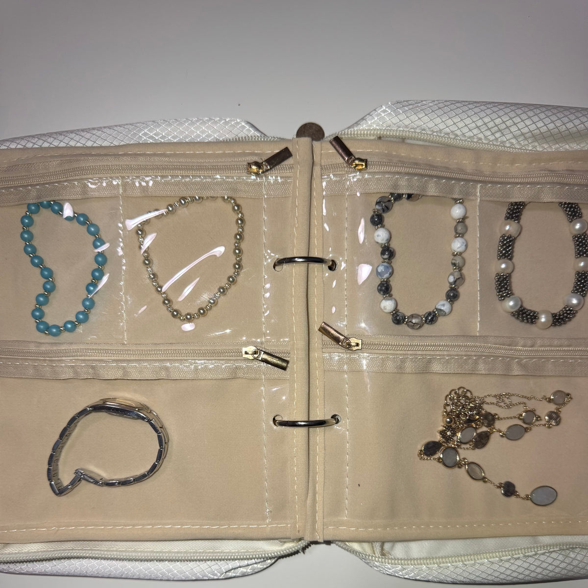 Velvet jewelry binder open, pages loaded with necklaces and bracelets, nothing tangled